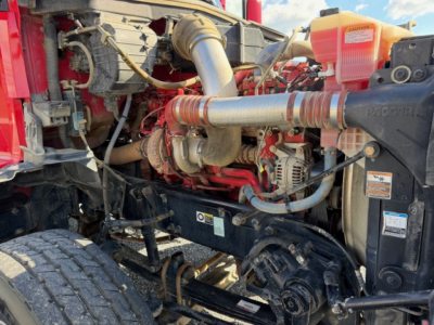 Kenworth T880 engine bay with exposed turbocharged diesel engine, intercooler piping, and fluid reservoirs visible.