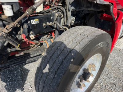Kenworth T880 truck front wheel and exposed engine bay with tire and suspension components visible.