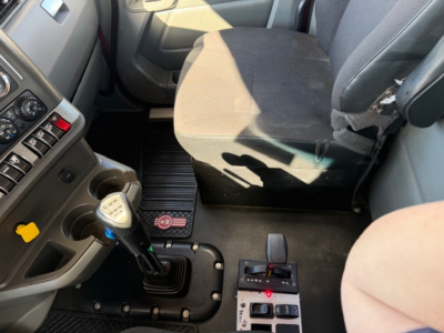 Interior cab area of Kenworth T880 showing gear shift lever, driver seat, and center console with control panel.