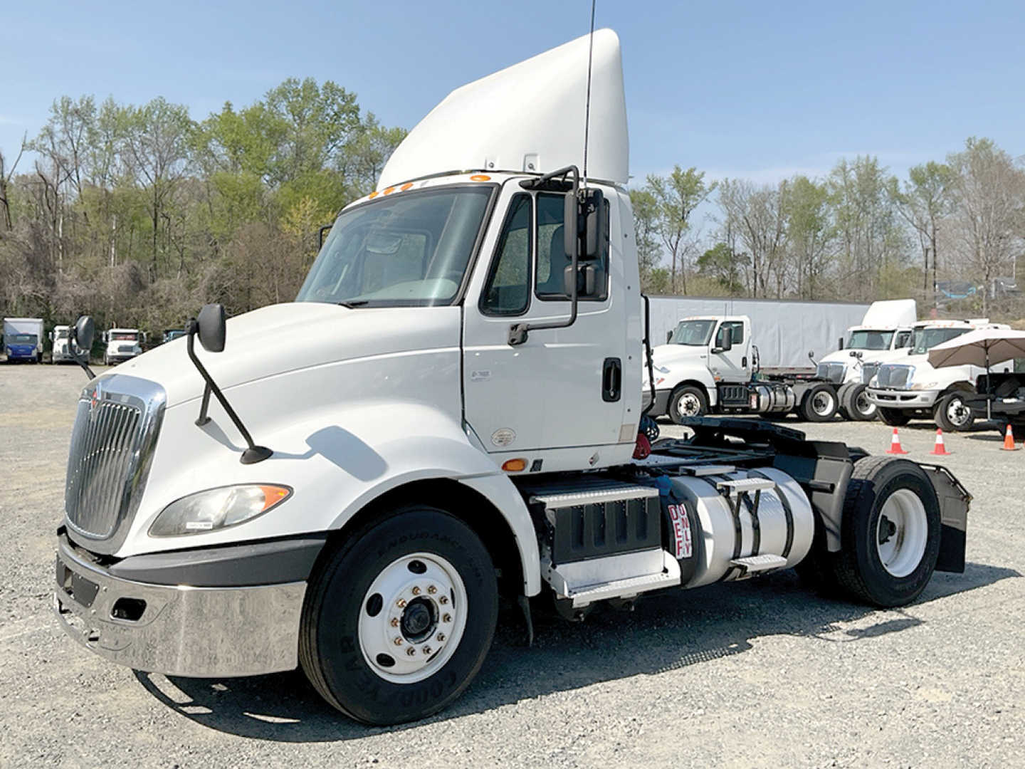 Truck cab with large white International ProStar+ tractor, front grille, side fuel tanks, and dual rear wheels parked in lot.
