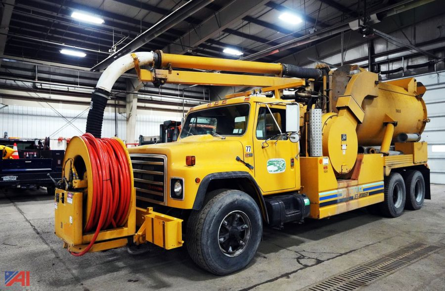 International F1954 vacuum truck with jet-rodder body in a warehouse, yellow with hose reel and jetting apparatus.