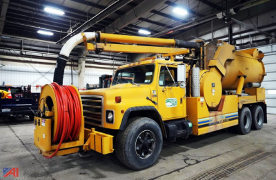 International F1954 vacuum truck with jet-rodder body in a warehouse, yellow with hose reel and jetting apparatus.