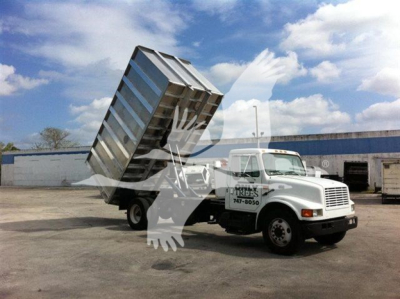 Dump truck with raised dump bed on a white cab chassis in a yard.