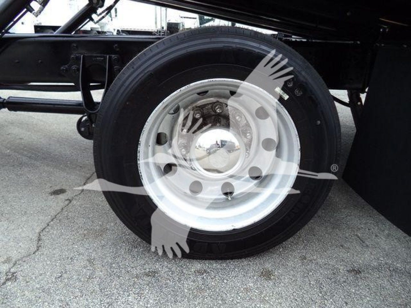 Truck wheel and chassis undercarriage with polished steel rim, tire, and suspension components.
