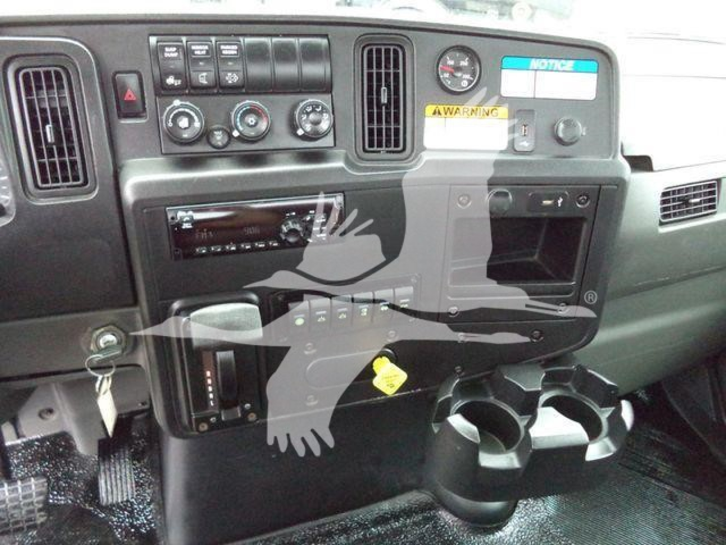 Dashboard of 2020 International MV rollback truck showing control panel, radio, climate knobs, cup holders, warning sticker, and ignition area.