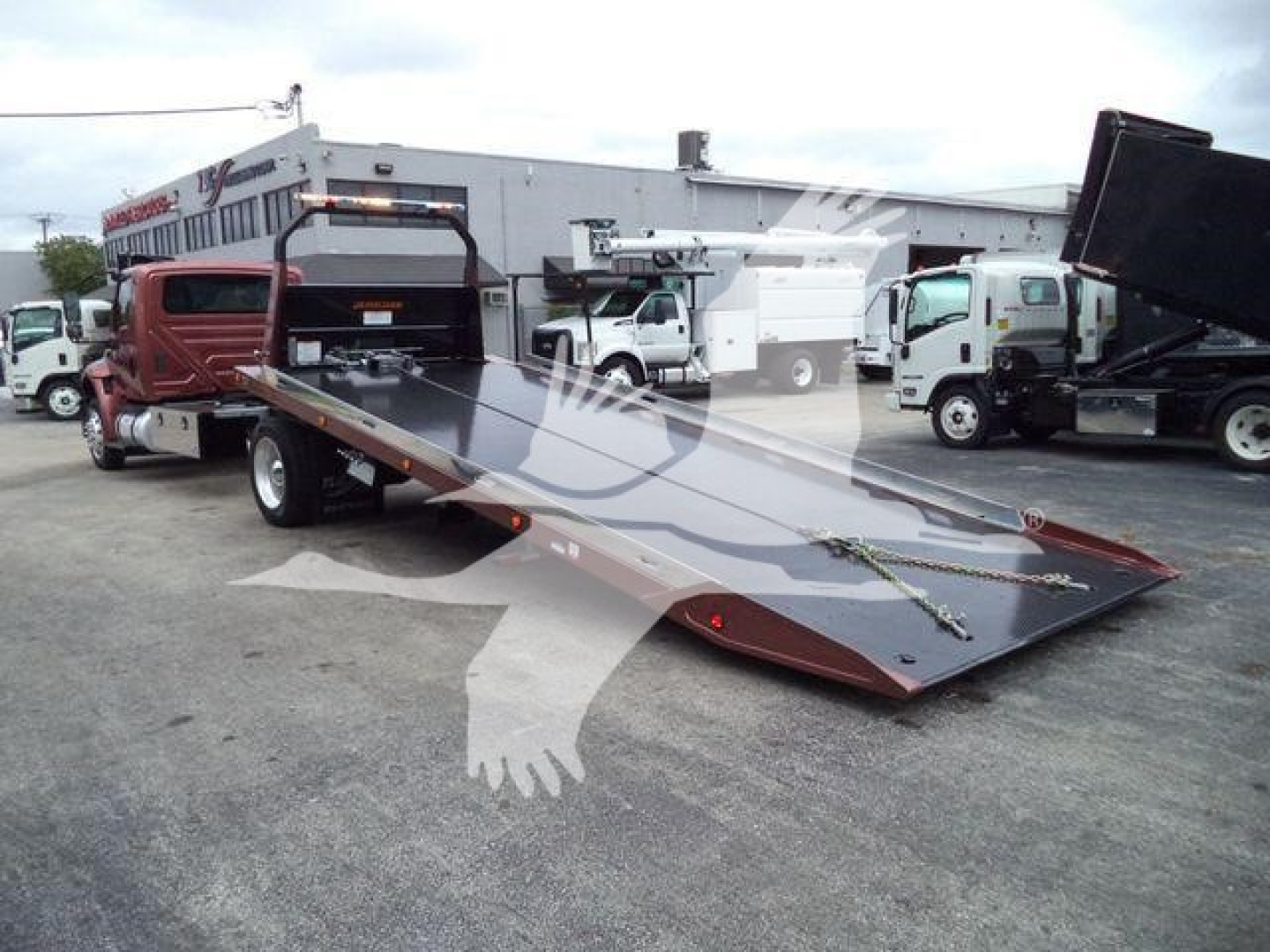 Truck with a large flatbed tilt bed in a dealership lot.