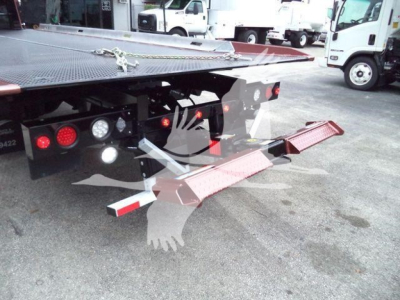 Tow truck rollback bed back view showing hydraulic wheel lift and rear red ramps with white reflective edges under a flatbed platform.