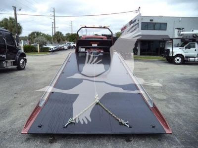 Tow truck rollover equipment: low-angle view of a black steel ramp with chains securing its front, rollback bed in a 2020 International MV dealership lot.