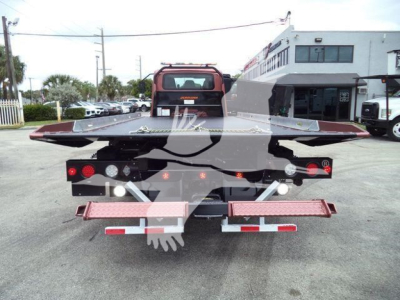 Truck bed of rollback tow truck viewed from rear, with hydraulic lift and safety lights visible.