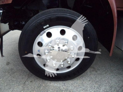 Wheel and hub of a truck with polished steel rim and black tire, partial red fender visible.