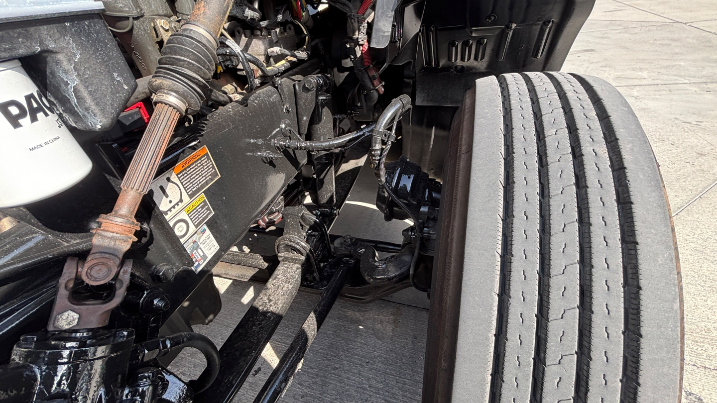 Kenworth T680 engine bay area showing front suspension and tire, with various hoses and a Pentair filter; visible labels and components.