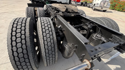 Kenworth T680 chassis showing rear triple-axle setup with tires and undercarriage components visible.