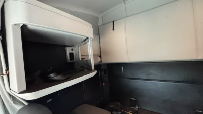 Cab interior view of a Kenworth T680 sleeper with a large overhead storage compartment and side paneling.