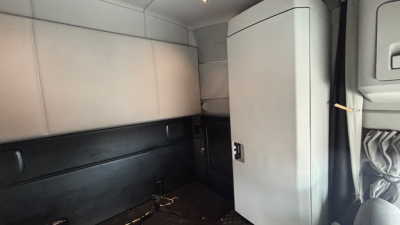 Cab interior of a Kenworth T680 sleeper showing side storage cabinet and seating area with light gray panels.