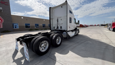 Tractor-trailer rear and cab of a white Kenworth T680 on a dealership lot, showing tandem axles and empty fifth-wheel area; no legible model text visible