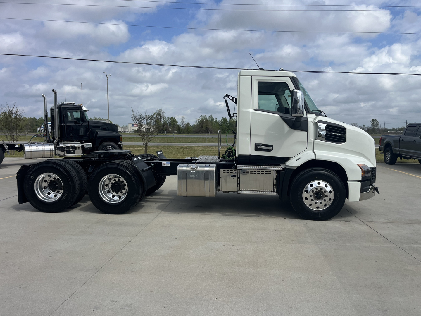 Mack AN64T daycab tractor side view showing cab, fuel tanks, and dual rear axles with chrome wheels.