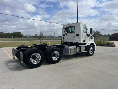 Mack AN64T conventional daycab truck in a parking lot, side rear view showing tandem axles and cab with white exterior.