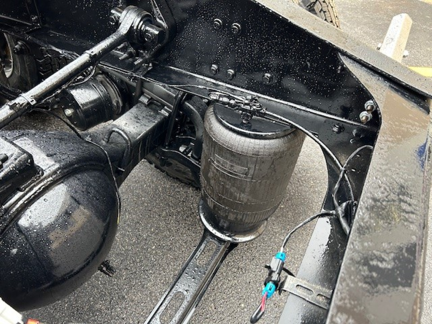 Air intake filter canister and chassis view of a Mack PI64T truck showing a cylindrical air filter canister and nearby hoses mounted under the frame.