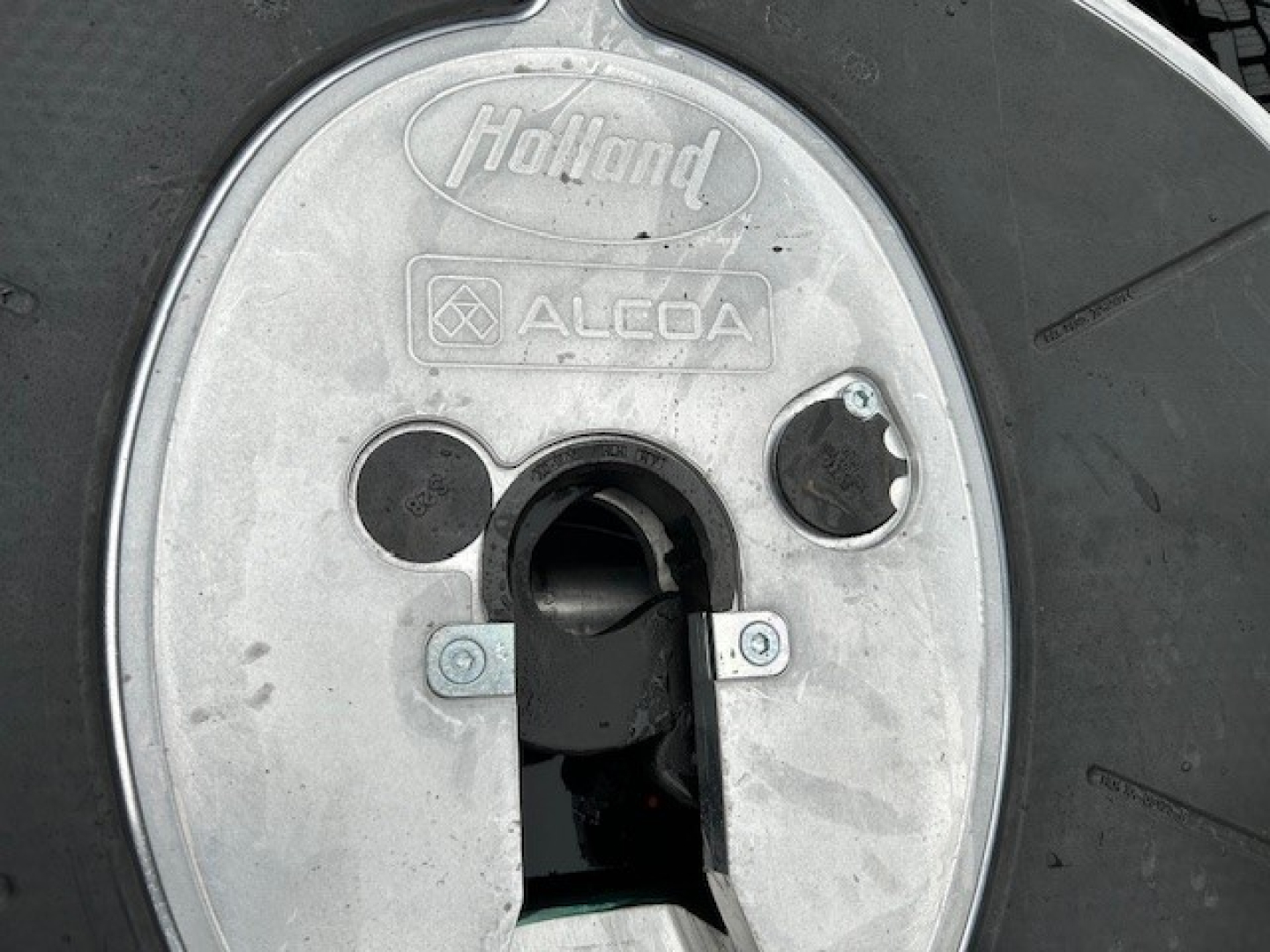 Wheel hub showing Holland ALCOA circular cover with keyhole area and hub cap for Mack PI64T truck wheel.