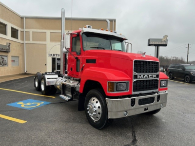 Mack PI64T conventional daycab truck in red parked outside dealership with 6x4 axle configuration, chrome bumper, Mack grille, and dual rear wheels.