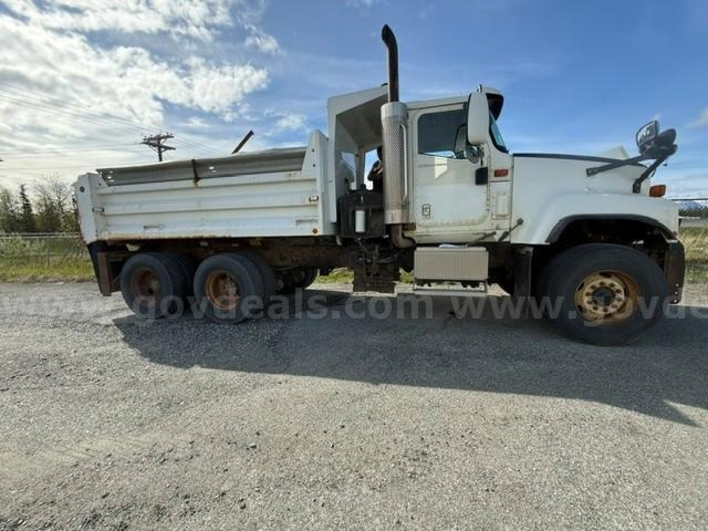 International 5500i dump truck side view showing white cab and dump bed with dual rear axles and heavy-duty tires.
