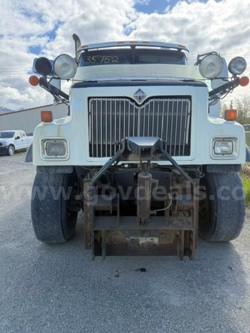 Front view of a white International dump truck (model 5500i) with a prominent grille, dual large headlights, and a mount for a plow or hitch at the bumper. Visible text on the image includes no clear brand label in the central badge area; t