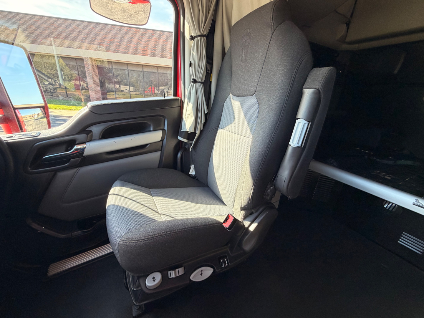 Kenworth T680 truck interior seat and driver area with dashboard and window view.