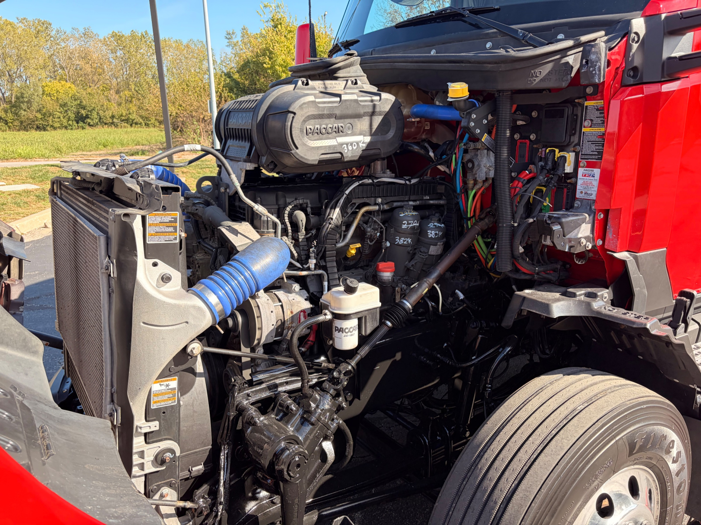 Kenworth T680 engine bay showing Cummins engine and radiator with hoses and components visible.