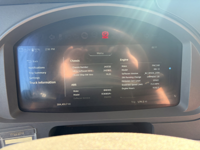 Kenworth truck dashboard display showing vehicle information including chassis number, engine make/model, software versions, and trip data.