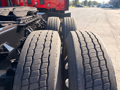 Kenworth T680 truck rear chassis with dual rear axles and heavy-duty tires; view focuses on the twin drive wheels and suspension components.