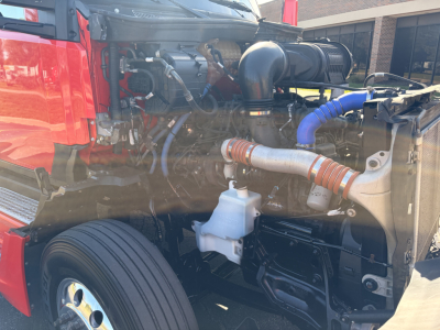 Kenworth T680 engine bay showing intake hoses and coolant reservoir with visible engine components.