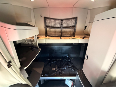 Truck cab interior showing bunk area and storage shelves in a Kenworth T680 sleeper