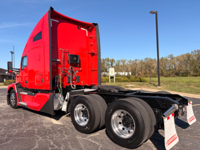 Red 2023 Kenworth T680 tractor with sleeper cab, rear view showing dual rear axles and chassis, no trailer attached.