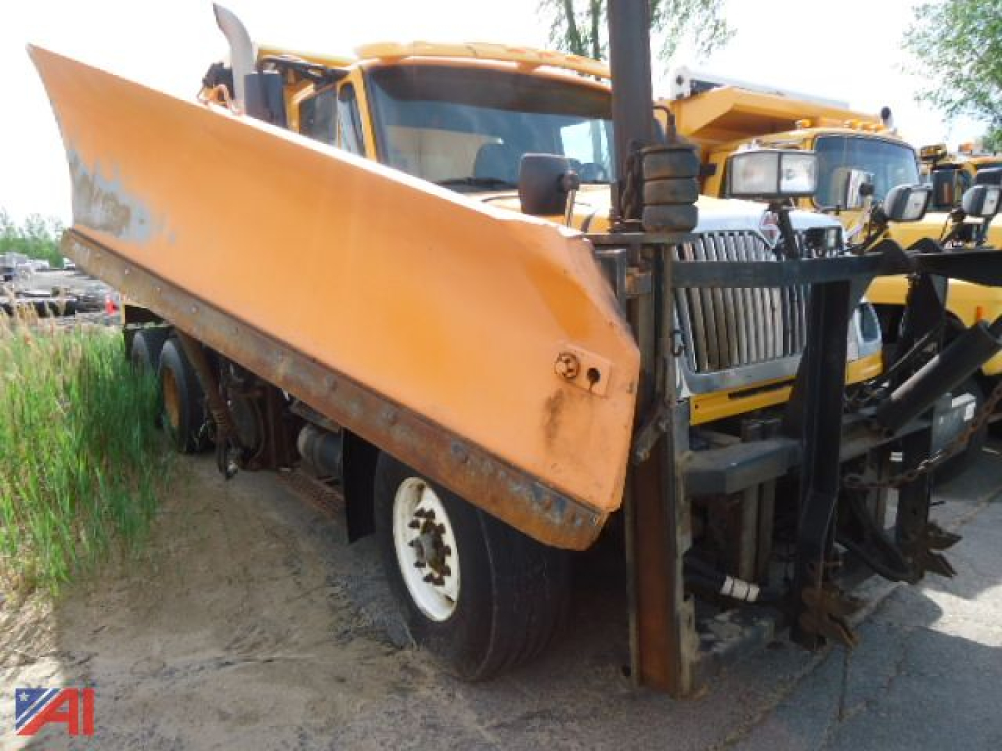 International WorkStar 7600 side dump bed showing orange dump box and chassis with front grille and wing attachment.