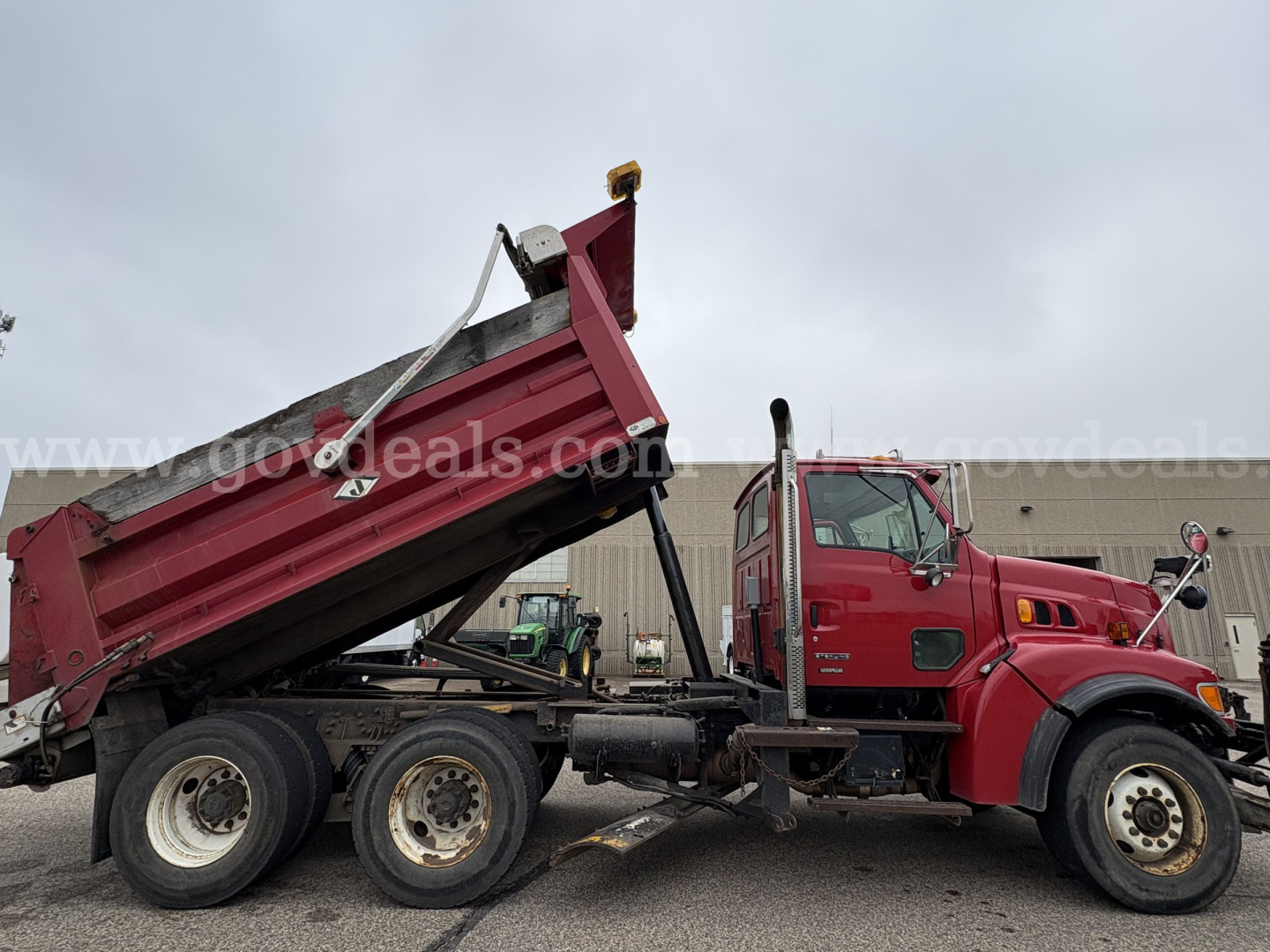 2001 Sterling LT9500 dump truck with red cab and dump bed raised, three-axle configuration, front grille and wheel details visible.
