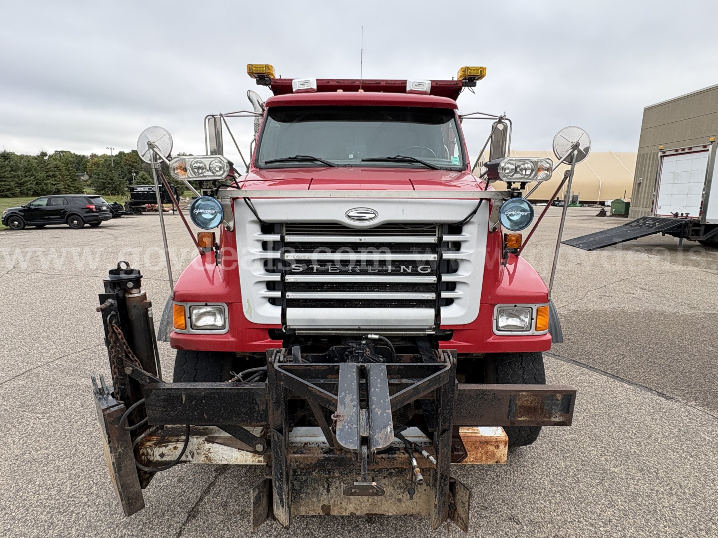 Front view of a red 2001 Sterling LT9500 plow truck showing snowplow mount and chrome grille, with round mirrors and amber warning lights.