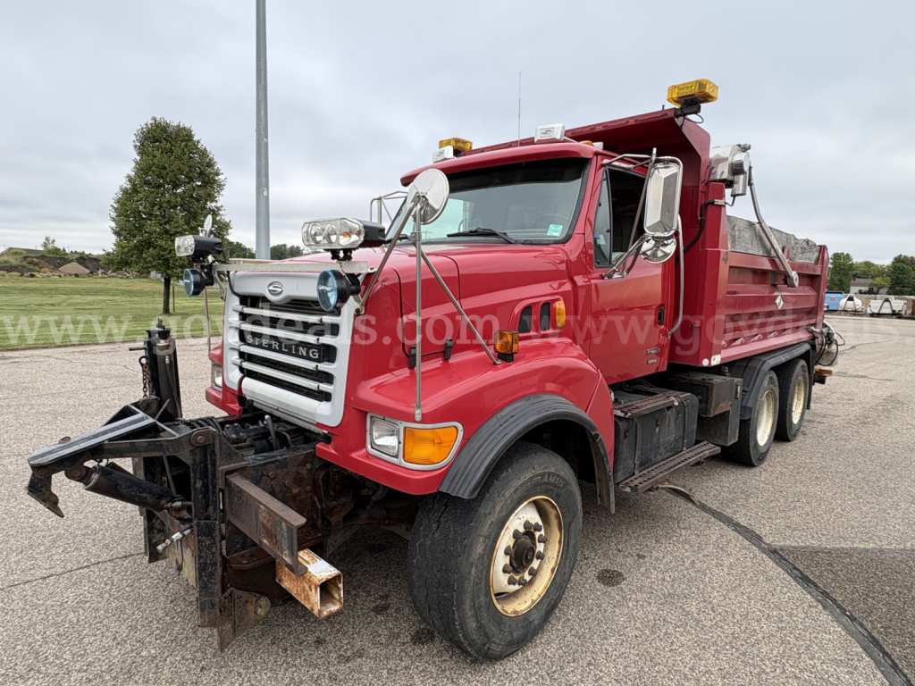 Red Sterling LT9500 dump truck with plow attachment, front grille, headlights, cab and dual rear axles. Visible text includes Sterling emblem on grille, truck body, and plow mount.