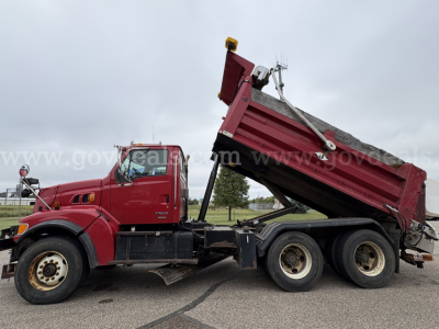 Side view of a red Sterling LT9500 dump truck with bed raised, showing rear dual wheels and hydraulic dump mechanism.