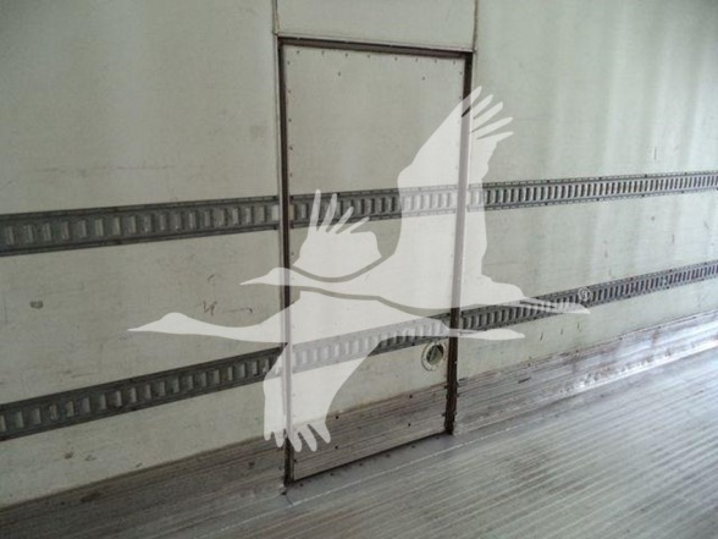 Truck trailer interior side door with seal marks, windowless metal wall.