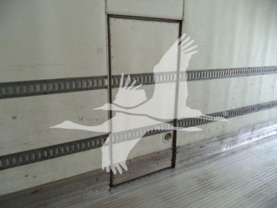 Truck trailer interior side door with seal marks, windowless metal wall.