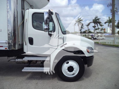 Truck cab side view of a 2023 Freightliner Business Class M2 106 with a box trailer, showing the front wheel, door, mirror, and side steps; no legible dashboard text visible.