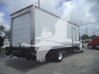 Box truck trailer attached to Freightliner M2 106 cab; side door visible; dual rear wheels; cargo box with ribbed metal walls; dealership lot in background.