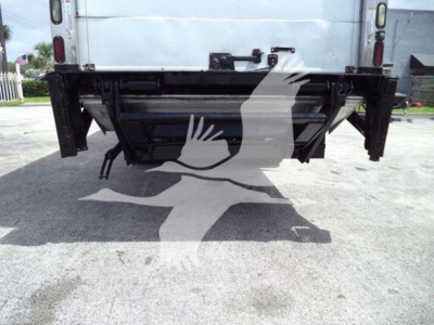 Rear view of freightliner m2 106 truck showing tailgate area and hitch with metal frame, undercarriage and pavement.