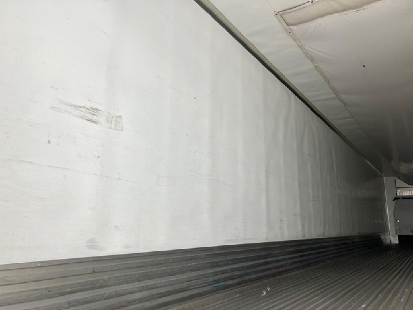 Trailer interior side wall and ribbed floor of a refrigerated trailer showing chrome interior with some scuff marks.