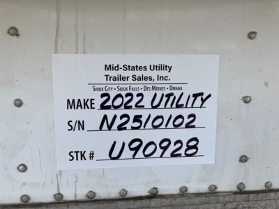 Trailer side with white label reading Mid-States Utility Trailer Sales, Inc. Make 2022 Utility, S/N N2510102, STK # U90928. VIN printed elsewhere; surroundings show riveted metal of refrigerated trailer.