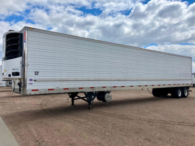 Trailer side view showing a white refrigerated semi-trailer with a Thermo King or similar reefer unit at the front and a rear set of tandem axles.
