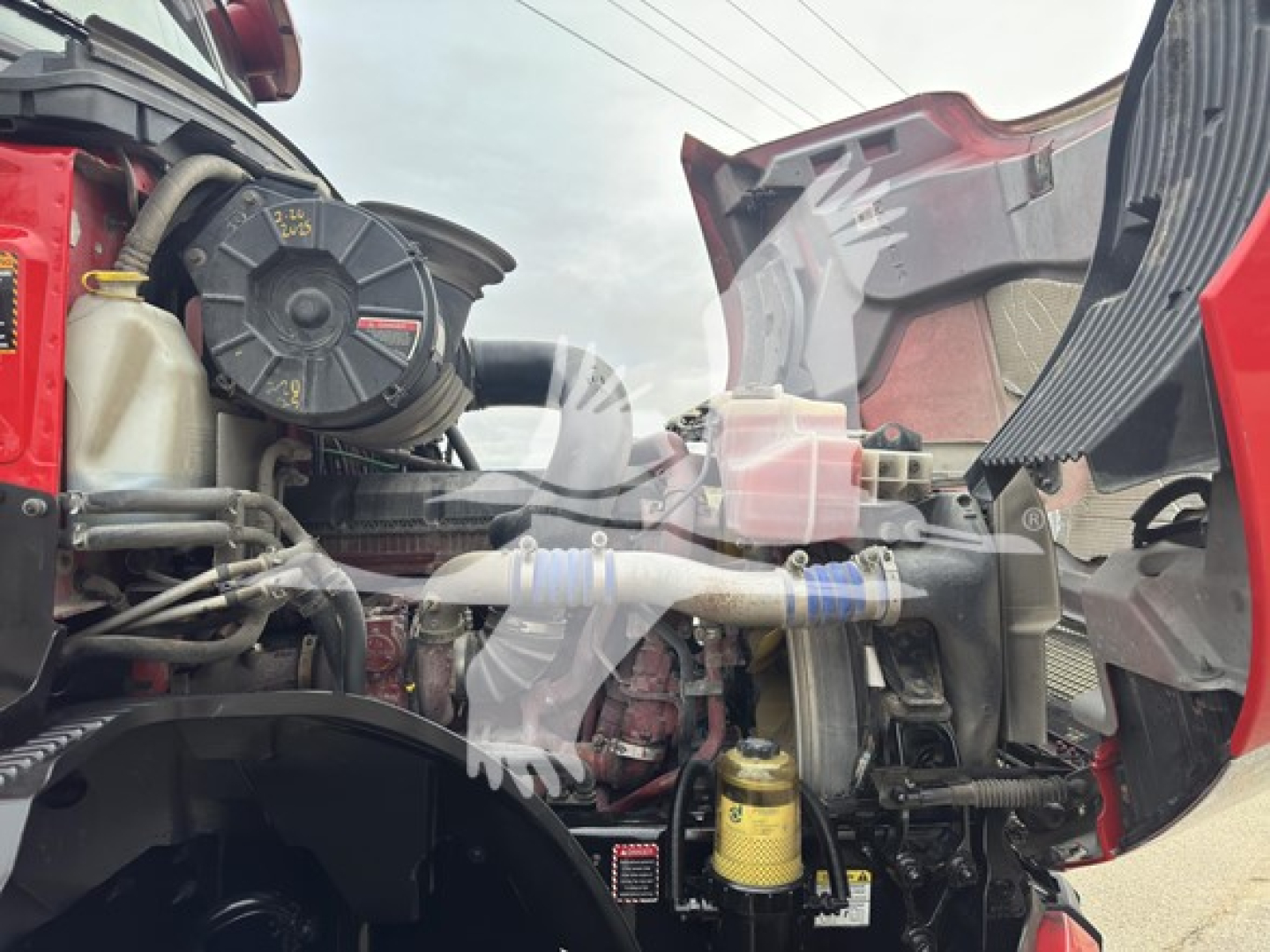 Mack Anthem 64T engine bay showing air intake, coolant reservoir, hoses, and yellow in-series filter with surrounding components in view.