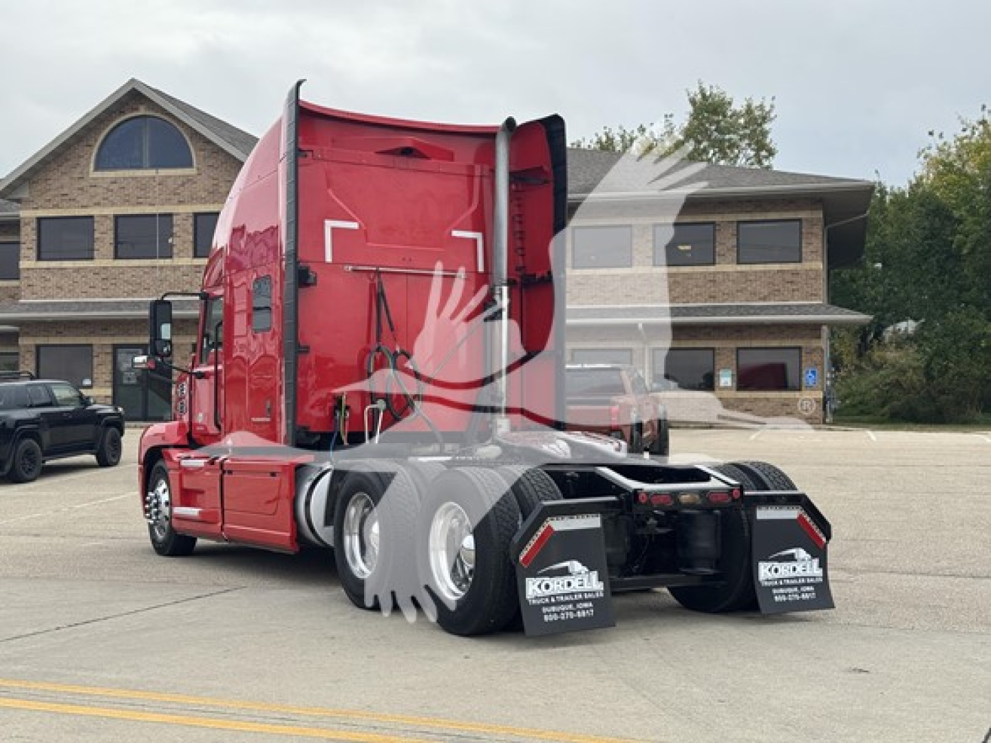 Truck rear/side view showing red 2019 Mack Anthem 64T sleeper tractor, twin rear axles, black mud flaps, and trailer kingpin area with reflective decals.