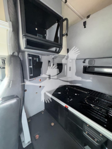 Interior of a 2019 Mack Anthem sleeper cab showing dashboard area with exposed panels, storage compartments, and steps; partial view of cab interior.
