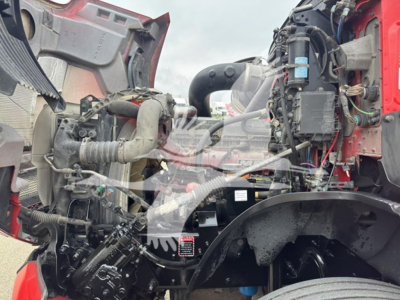 Mack Anthem 64T engine bay with exposed components, hoses, and wiring in view; shows turbocompressor, coolant lines, and intake piping.